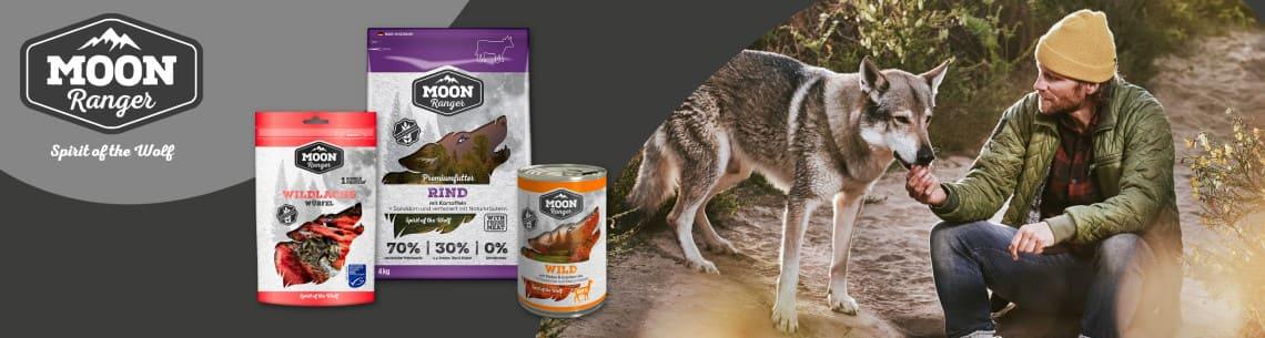 Moon Ranger Hundefutter mit Outdoor‑Szene Moon Ranger Hundefutterprodukte stehen neben einer Szene mit einem Hund, der von einer Person gefüttert wird.
