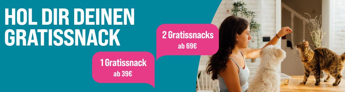 Jetzt Gratis-Snack sichern Aktionsbanner für Gratis-Snacks. Links auf türkisfarbenem Hintergrund der Hinweis „Hol dir deinen Gratissnack“. Mittig zwei pinke Aktionsflächen mit den Angaben „1 Gratissnack ab 39 €“ und „2 Gratissnacks ab 69 €“. Rechts eine Person an einem Tisch mit einem weißen Hund und einer Katze. Hinweis: Gratis-Snack-Aktion ab 39 € Bestellwert.